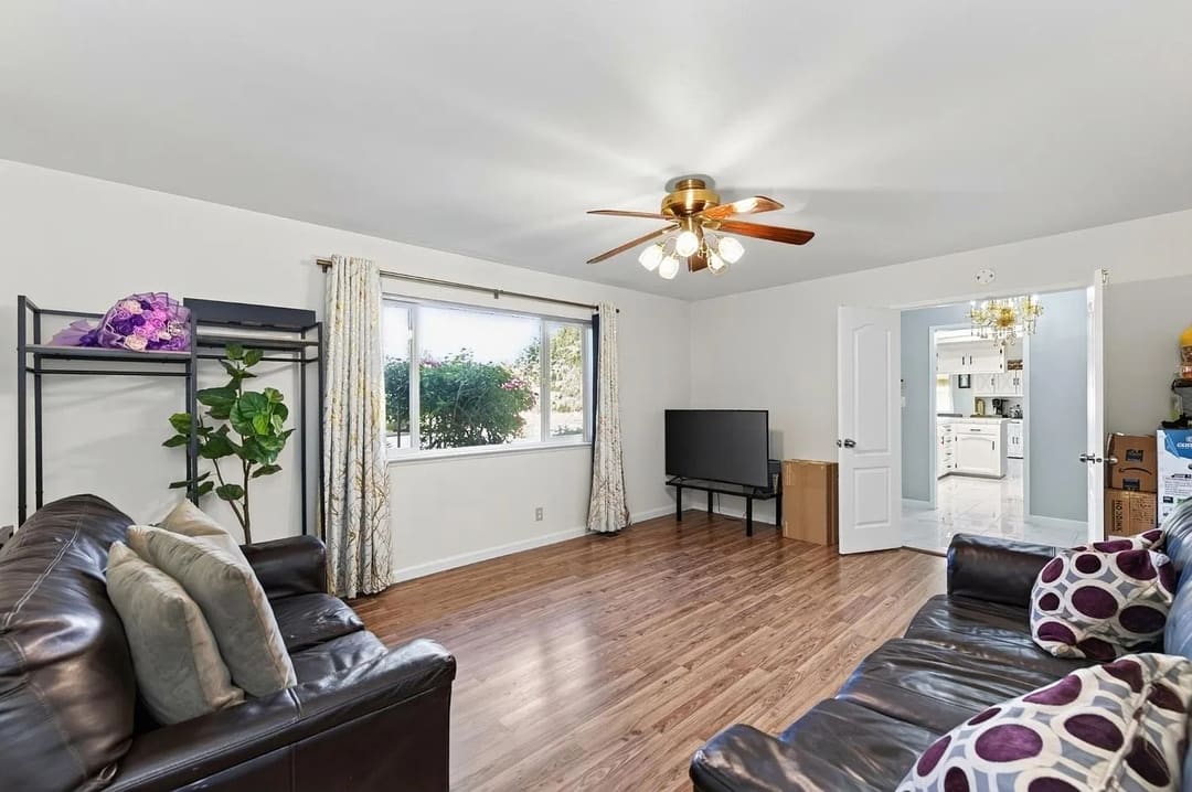 A living room with two dark leather sofas facing a wall-mounted television on a low stand.