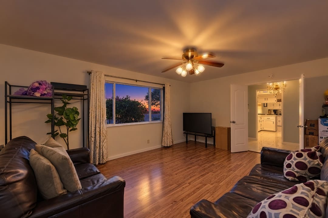 A living room with two dark leather sofas facing a wall-mounted television on a low stand.